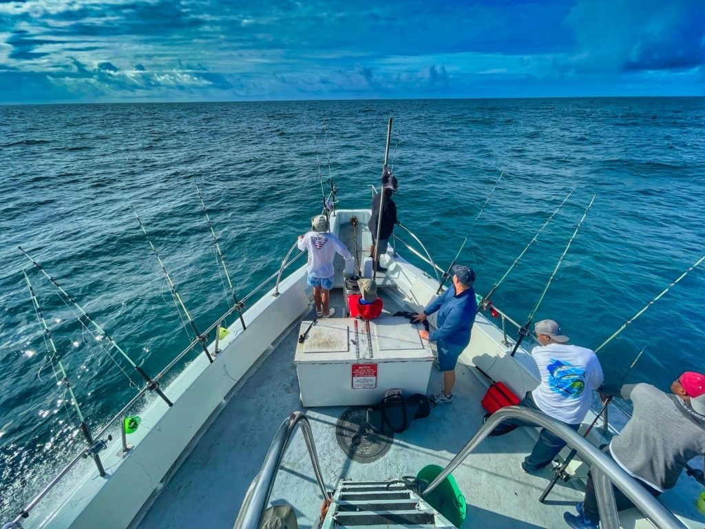 People fishing on boat in open ocean under cloudy sky.