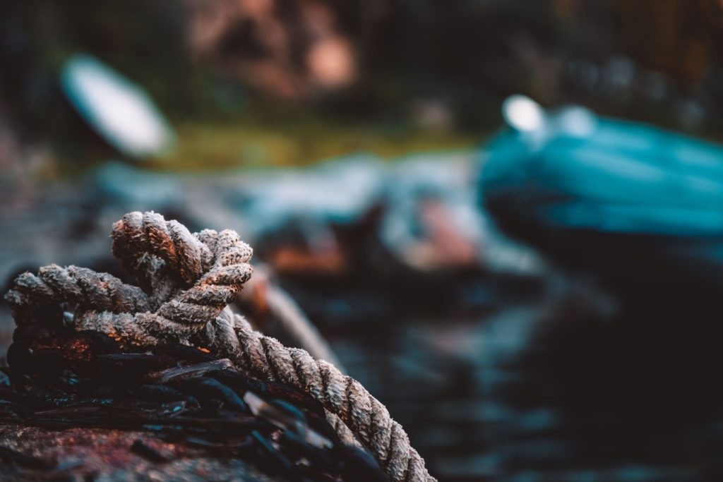 Close-up of a thick rope tied around a log with blurred background.